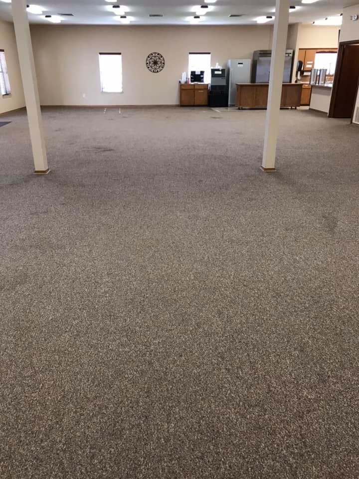 A large empty room with a carpeted floor and pillars.