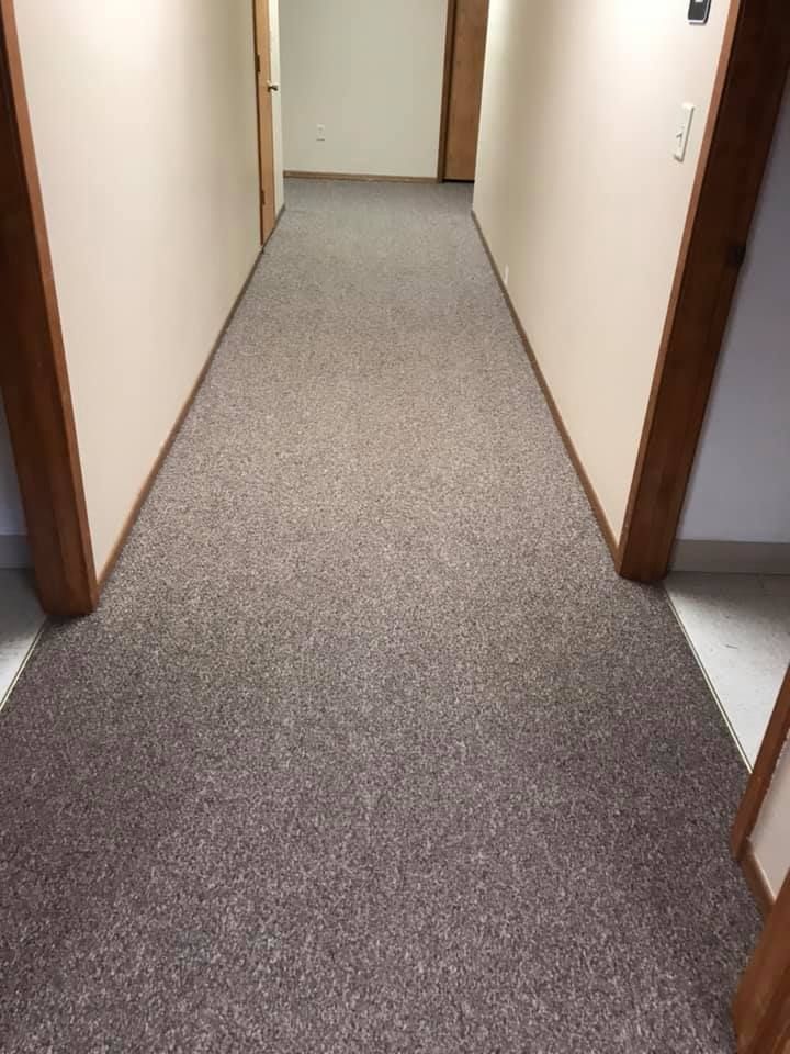 A long hallway with a carpeted floor and wooden doors.