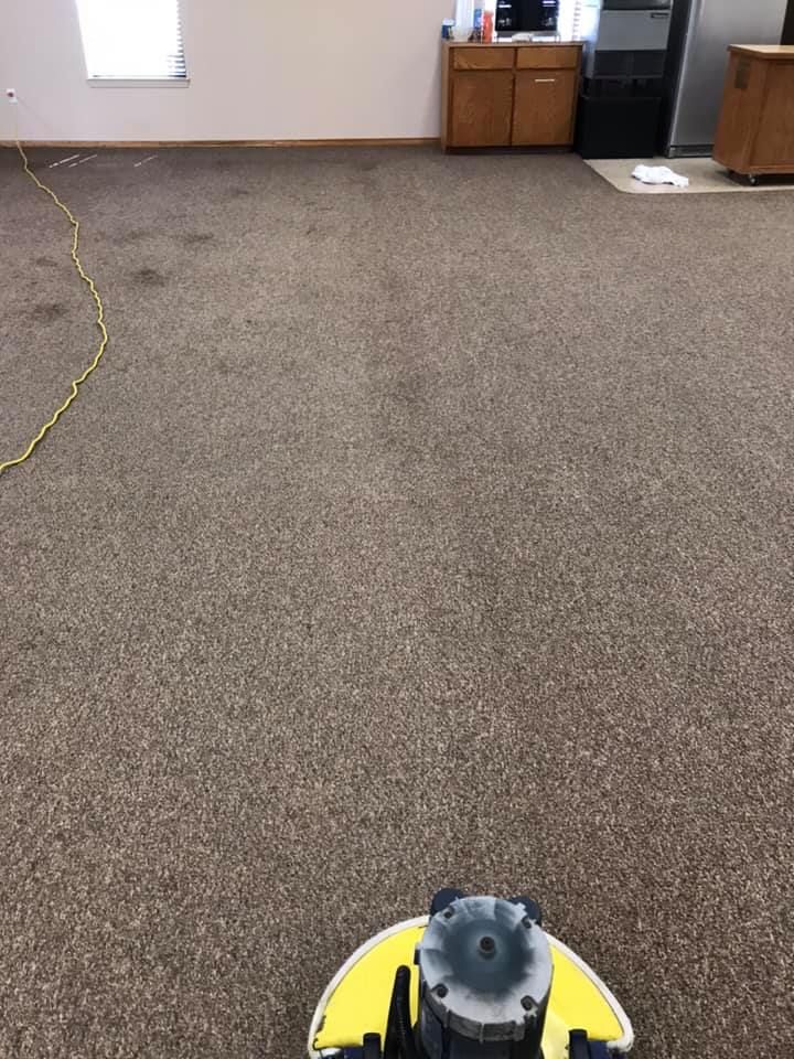 A machine is cleaning a carpet in a room.