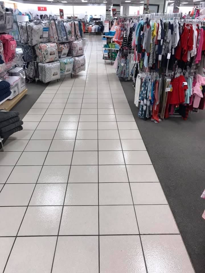 A tiled floor in a store with clothes hanging on racks.