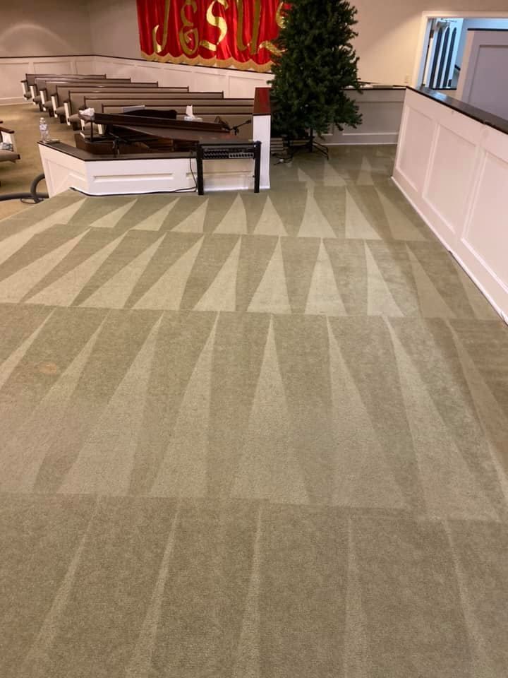 A carpeted floor in a church with a christmas tree in the background.