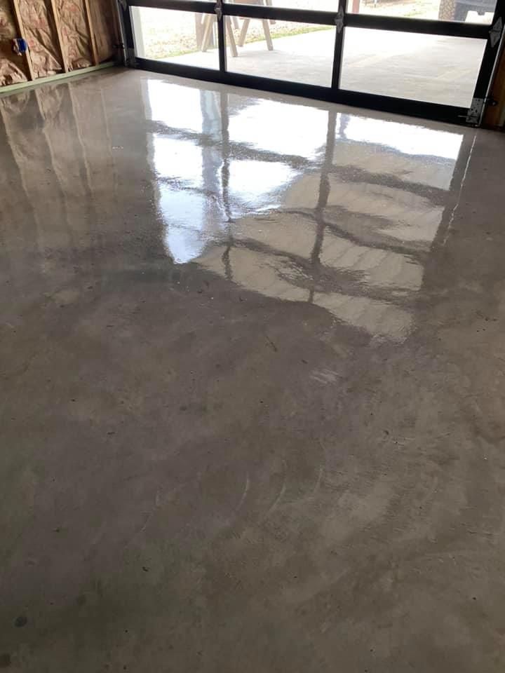 A shiny concrete floor in a room with a large window.