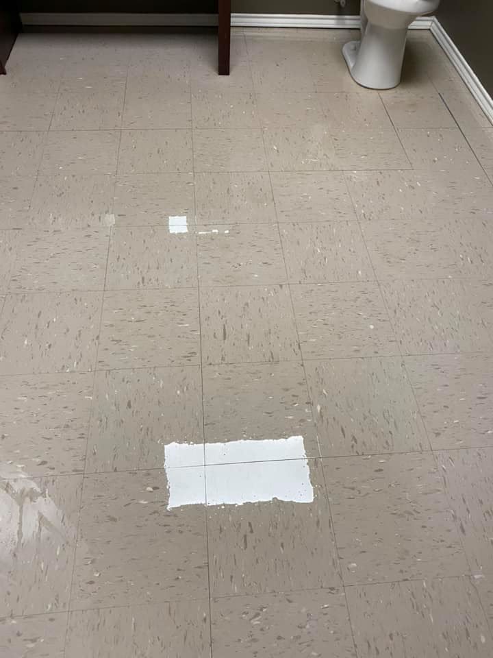 A bathroom floor with a toilet and a piece of paper on it.