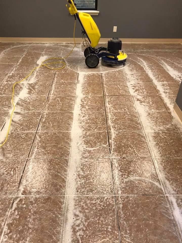 A yellow machine is cleaning a tiled floor in a room.