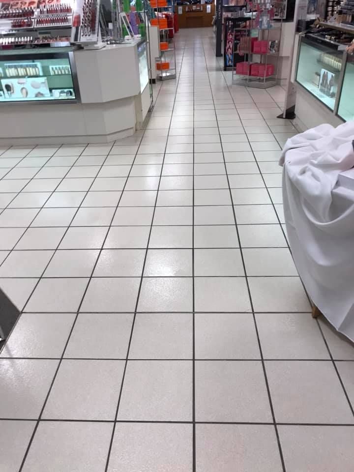 A white tiled floor in a store with a table in the middle.