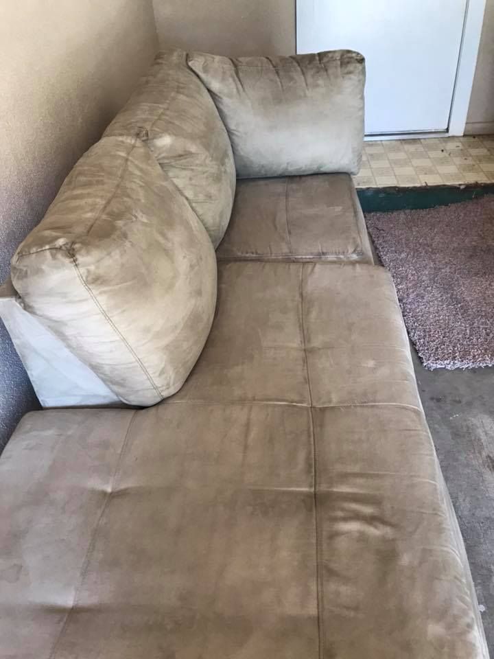 A brown leather couch is sitting in a room next to a door.