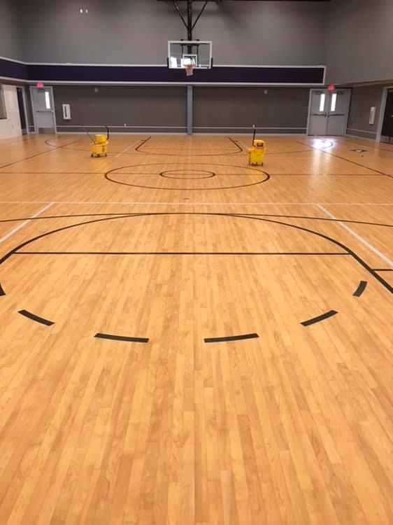 A basketball court with a wooden floor and a basketball hoop.