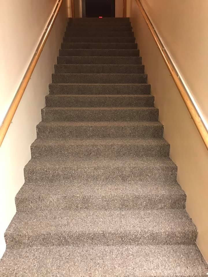 A set of stairs with a wooden railing and a carpeted floor
