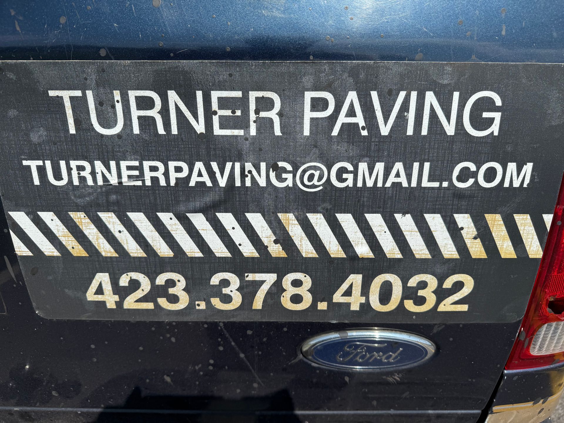 Black vehicle rear with a Turner Paving business magnet. It has company name, email, and phone number.