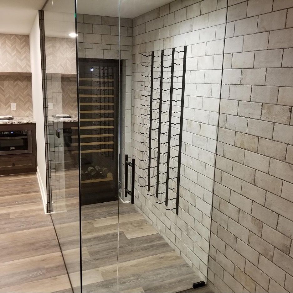A wine cellar with a glass door and a brick wall