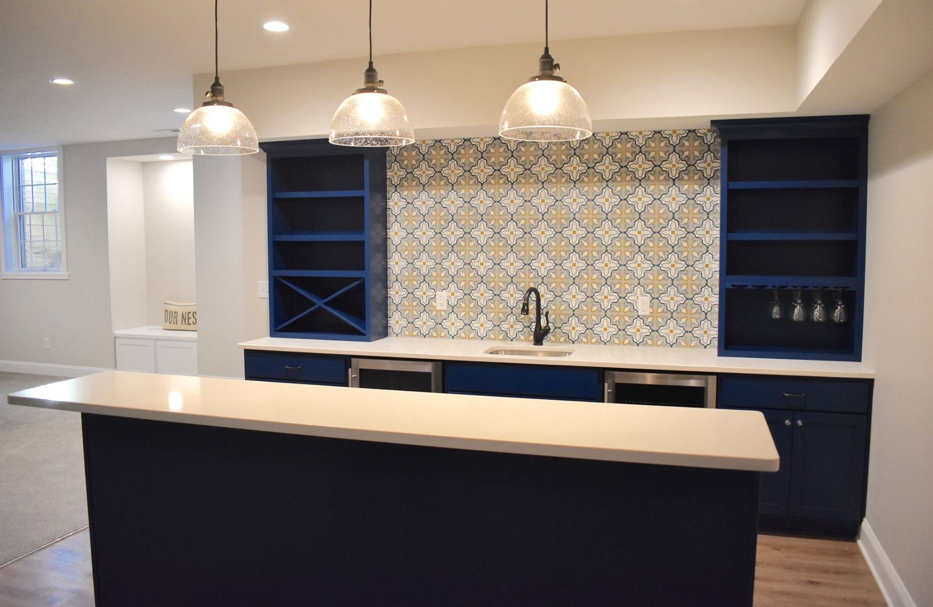 A finished basement kitchen with blue cabinets and a white counter top