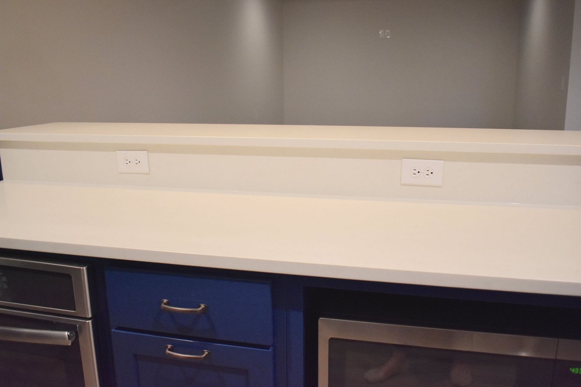 A basement kitchen with blue cabinets and stainless steel appliances