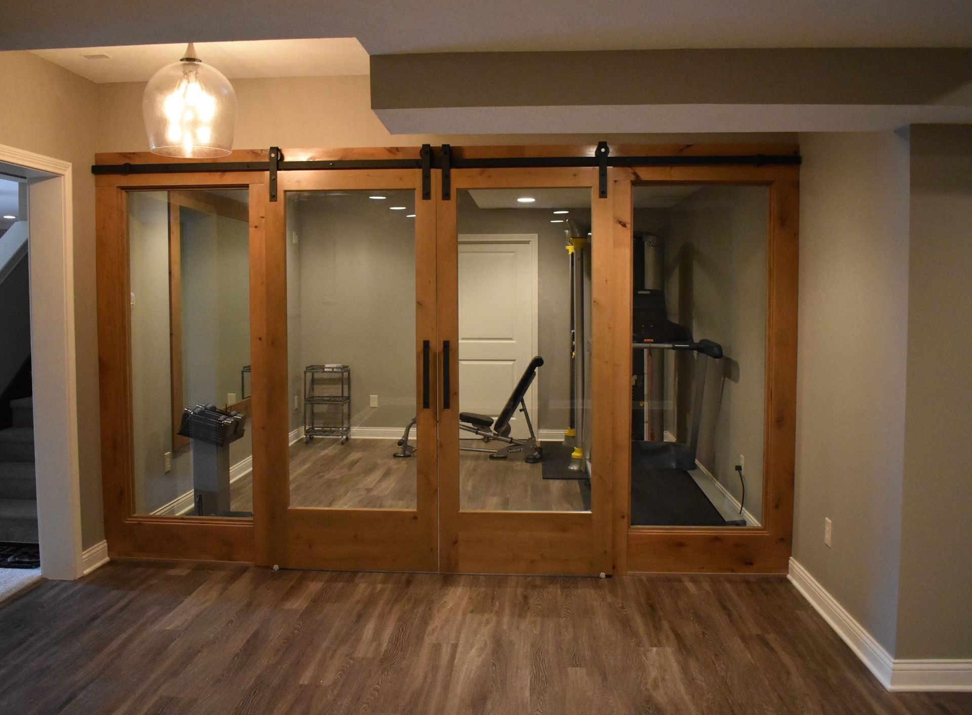 A basement with sliding barn doors and a treadmill.