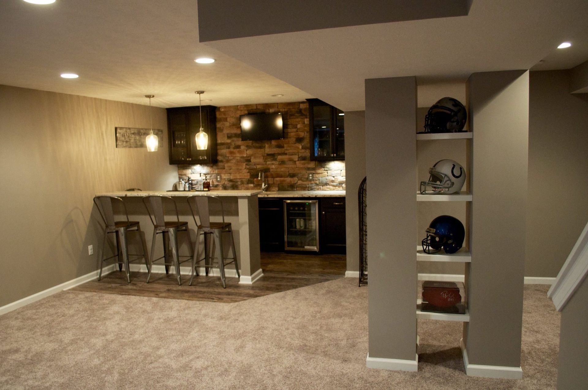 A basement with a bar , stools and shelves.