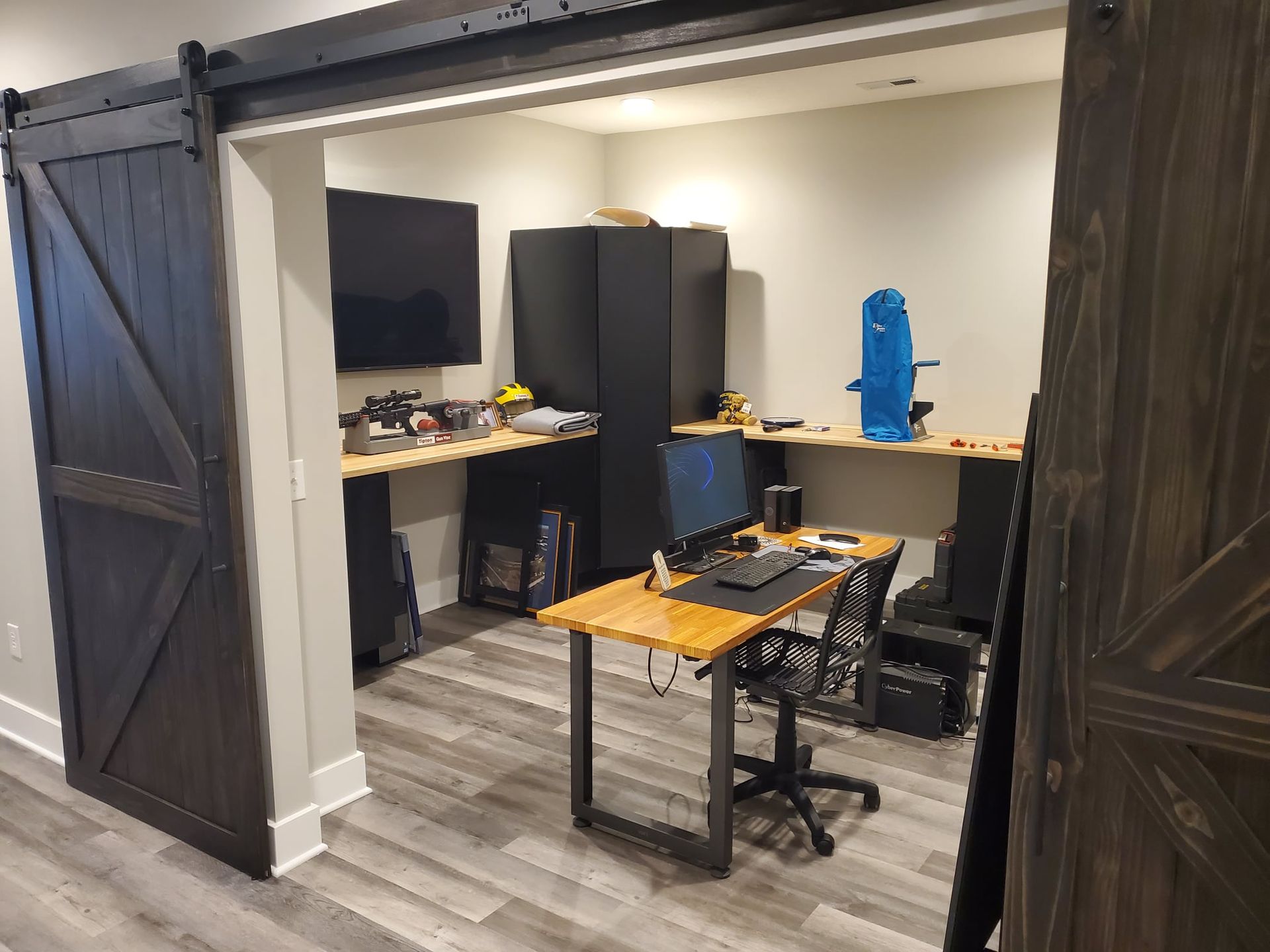 A basement office with sliding barn doors and a desk with a computer on it.