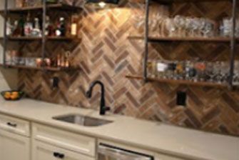 Bar area with a brick backsplash, shelves, sink, and white cabinets.