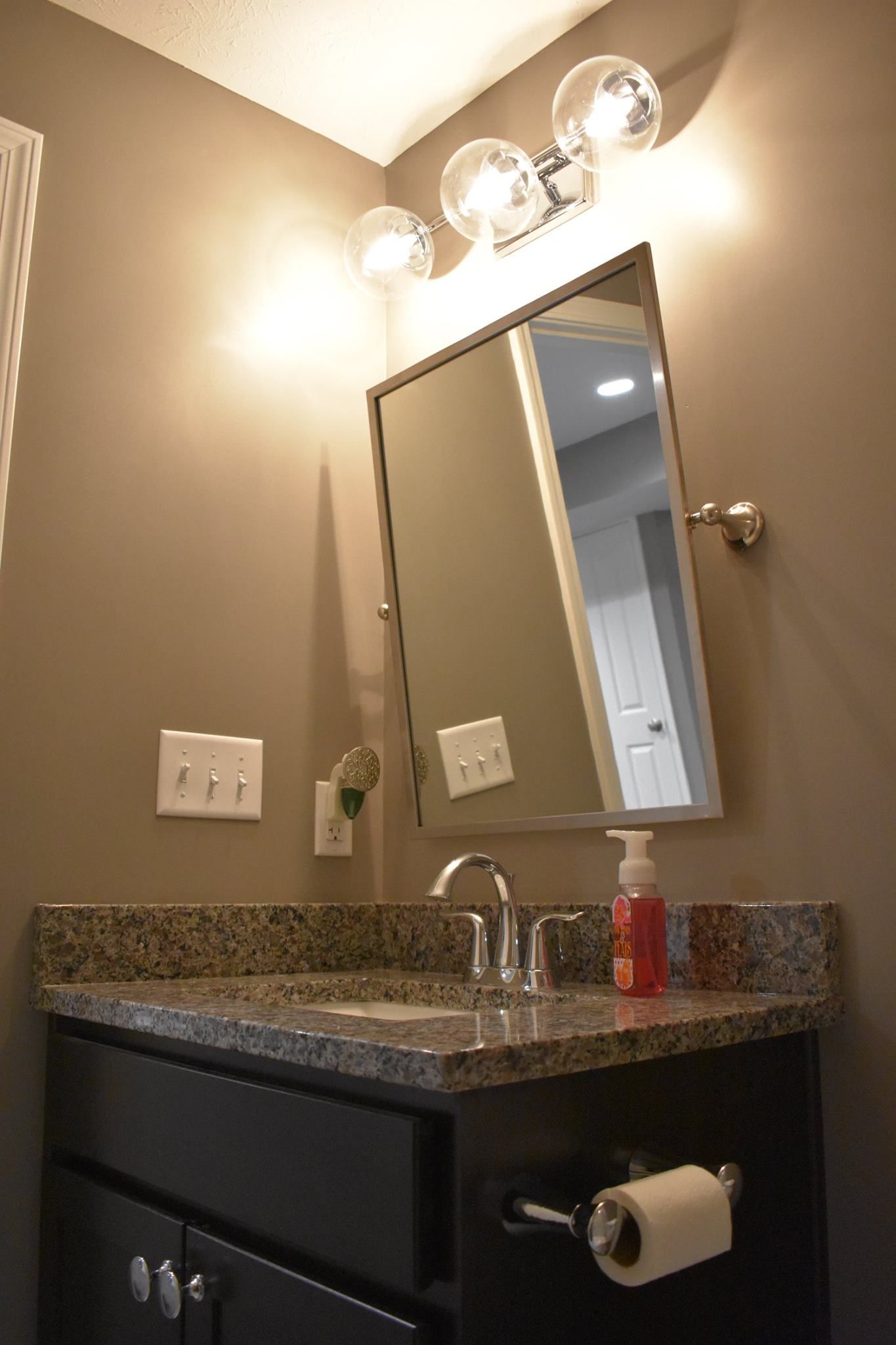 A bathroom with a sink, mirror, and light fixtures
