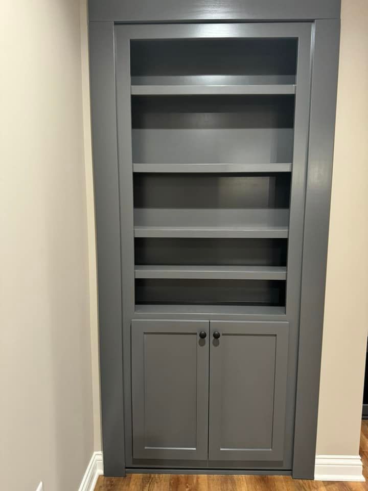A gray bookcase with shelves and doors in a room