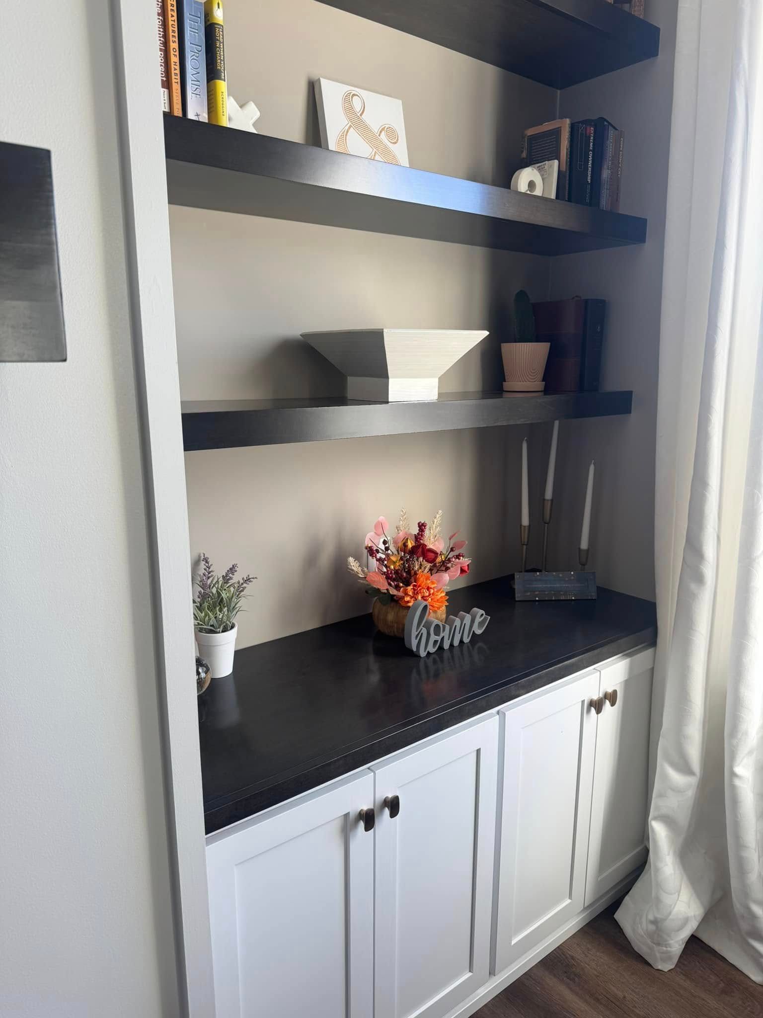 A bookshelf with black shelves and white cabinets