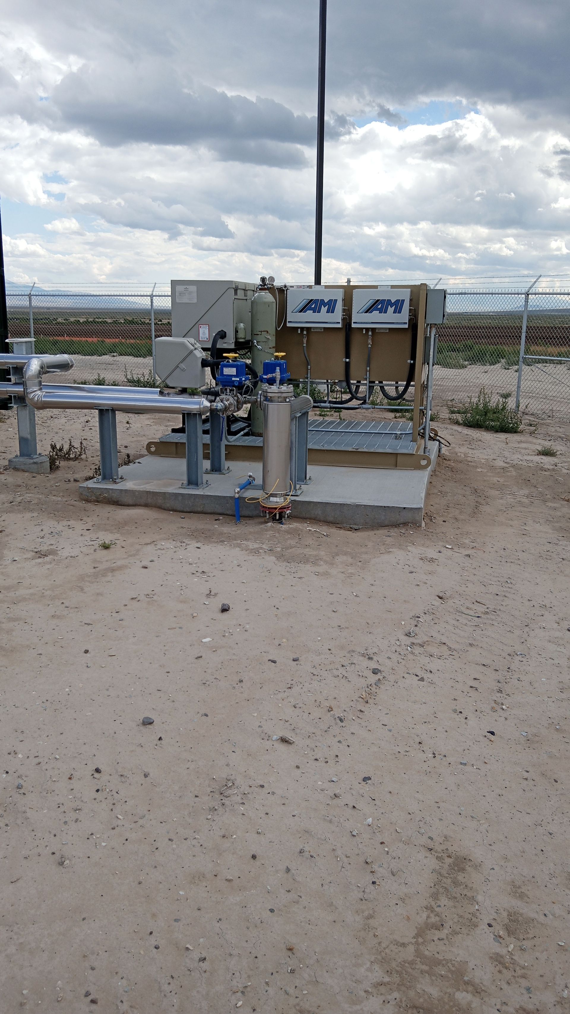 A large electrical box is sitting in the middle of a dirt field.
