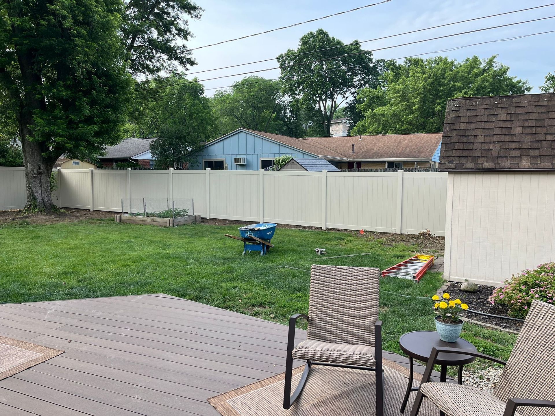 Backyard with deck, fence, and shed; lawn and trees under a cloudy sky.