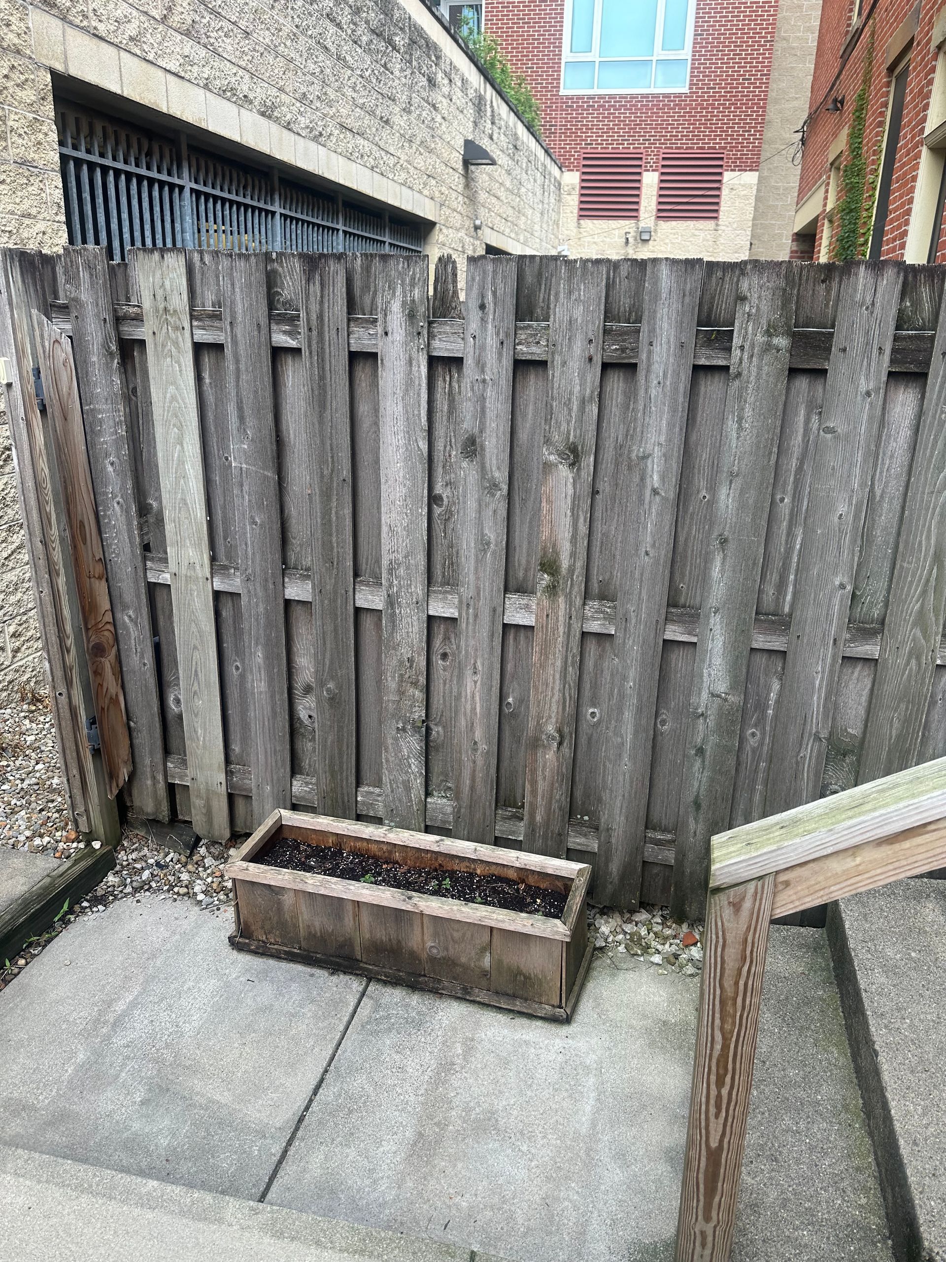 Wooden fence with a planter box on a concrete surface.