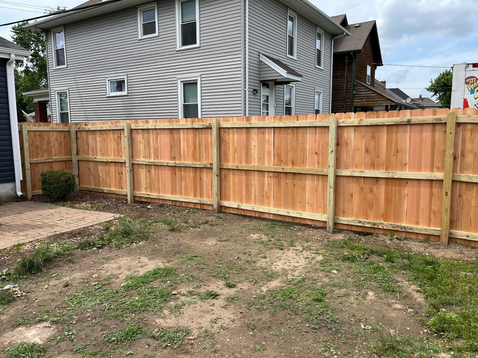 Wooden fence enclosing a backyard with a house in the background.