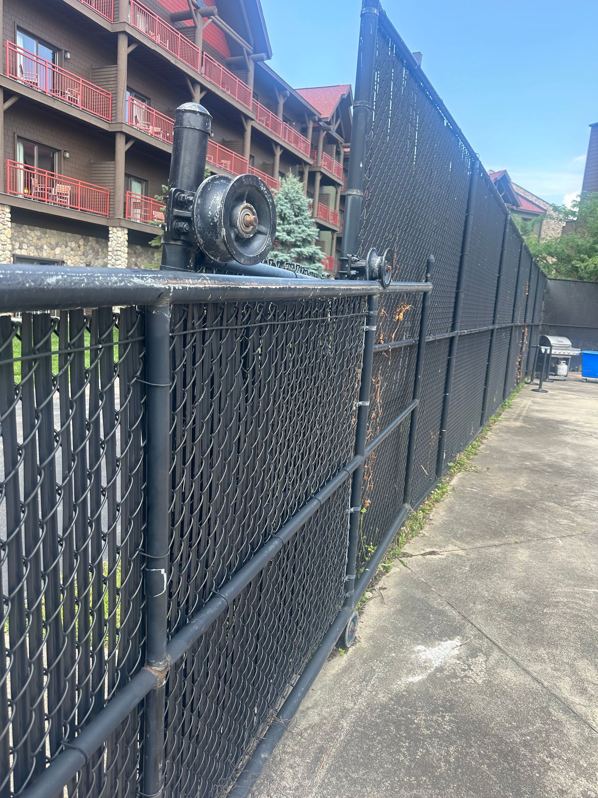 Black chain-link fence with a structure behind it.