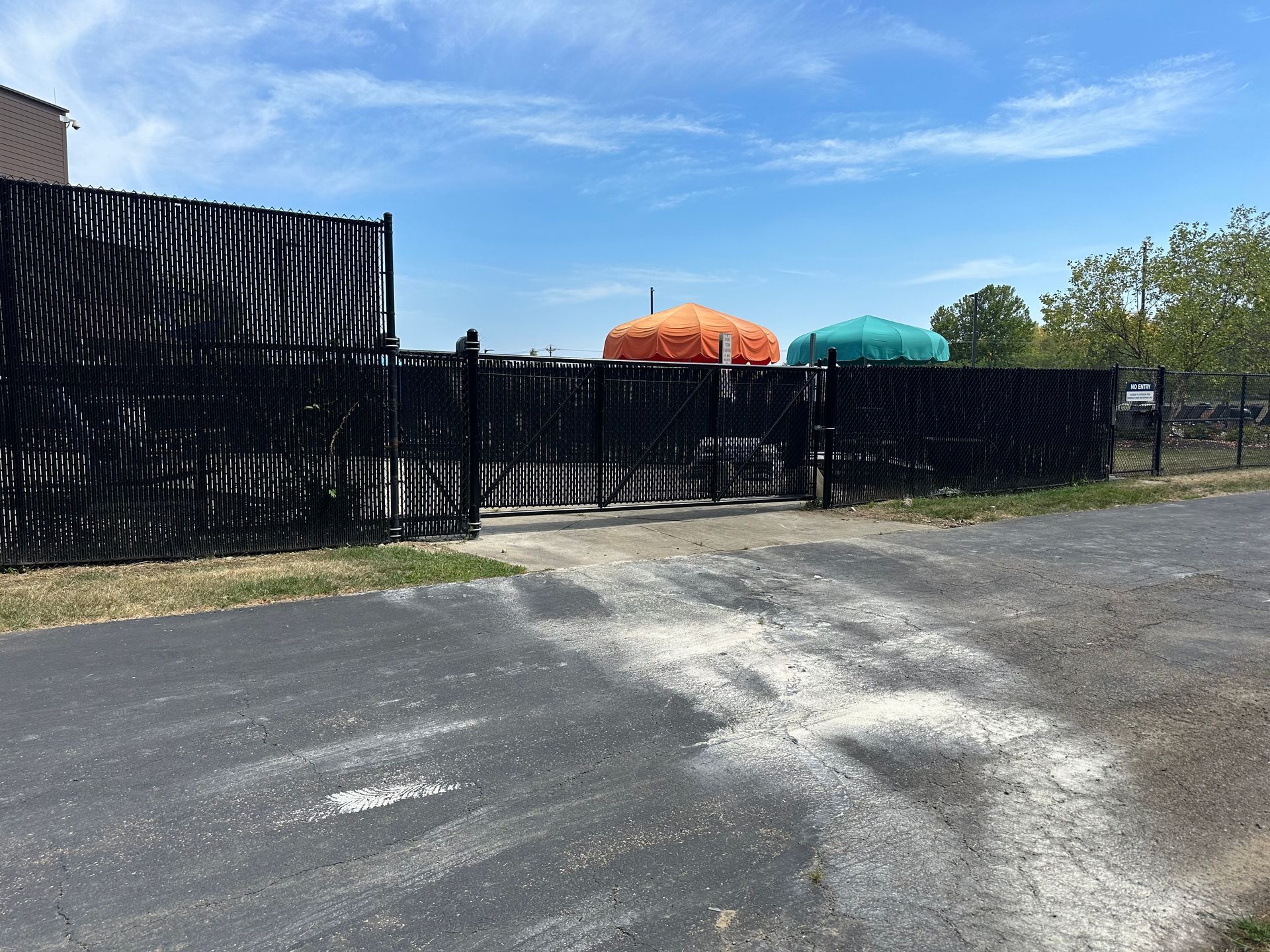 Black fence with open gate leads to colorful domes under a blue sky.