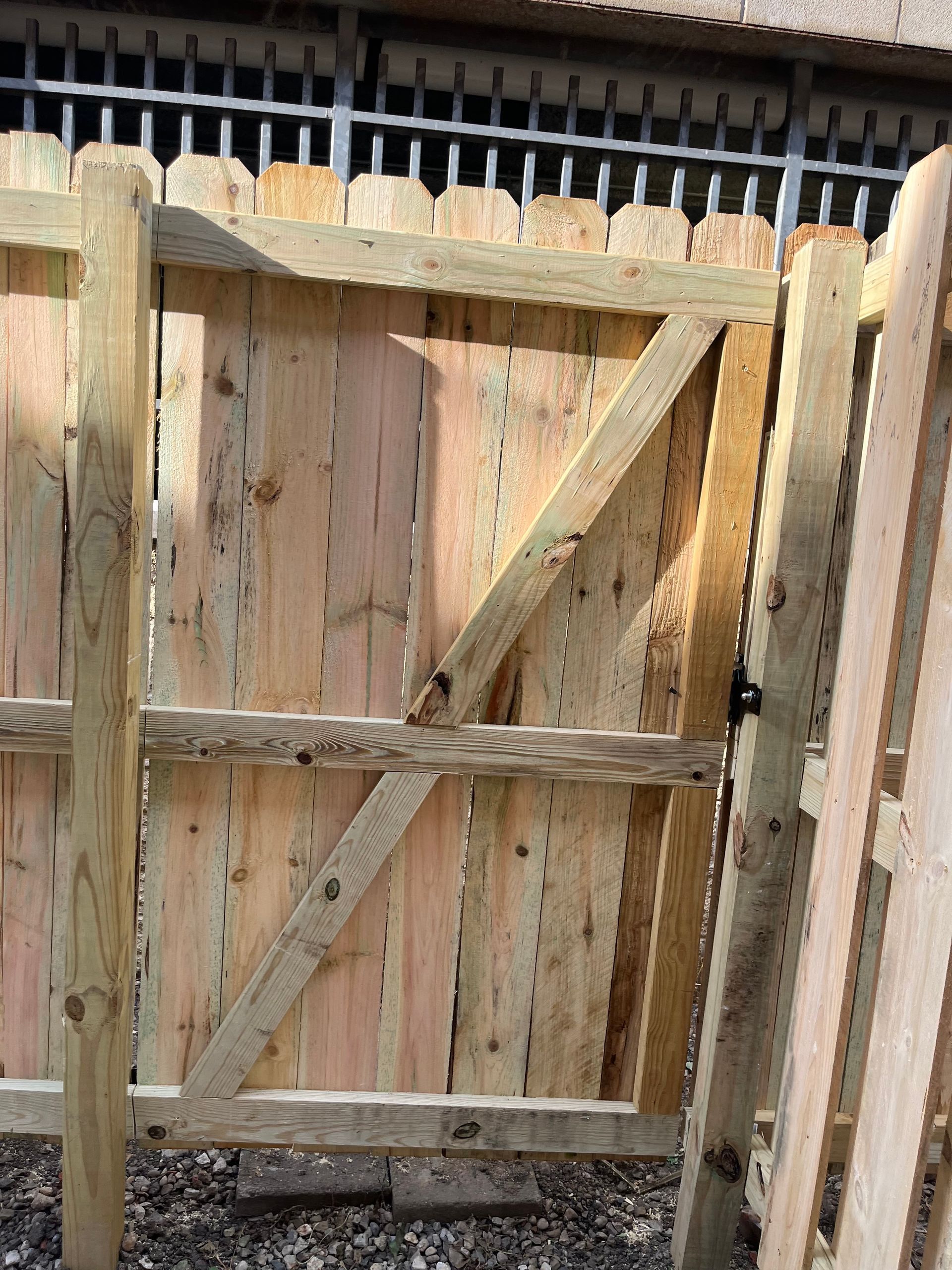 Wooden gate with diagonal brace, attached to a wooden fence.