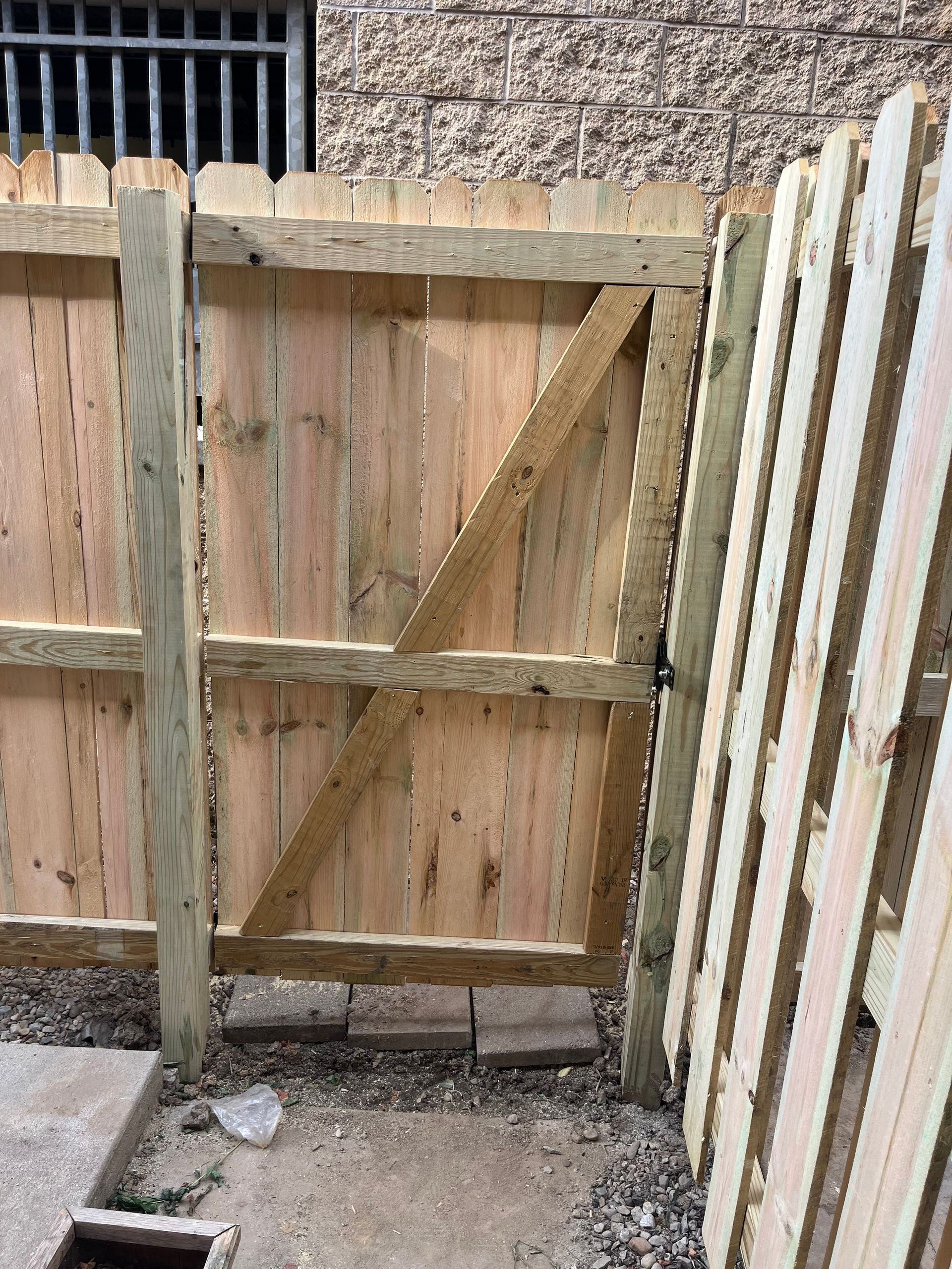Wooden gate in a wooden fence; a diagonal brace provides support.
