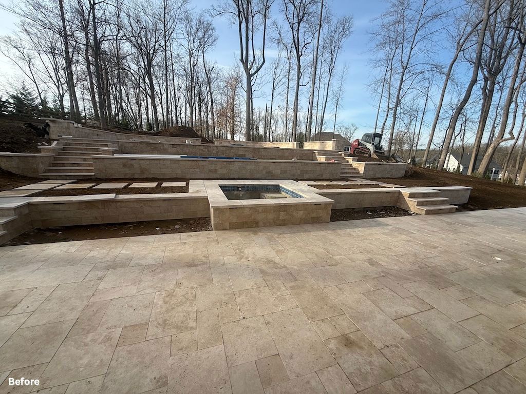 Outdoor terraced stone seating steps around a central fire pit under bare trees in a park