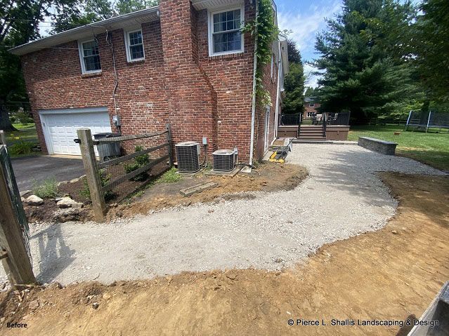 Brick house beside a new gravel driveway and walkway, with a garage and fenced yard.