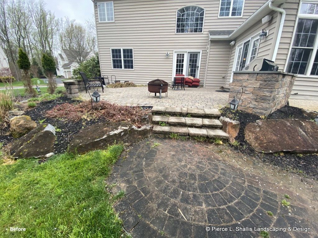 Backyard patio with stone steps, mulch beds, and a beige house exterior