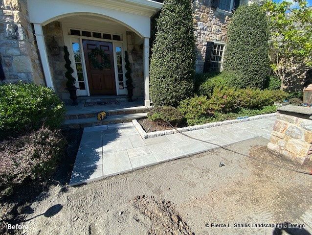 Stone walkway leading to a front door with trimmed hedges and stone landscaping