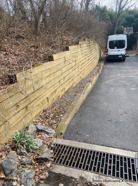 Street beside a yellow retaining wall, with a white van parked ahead and a storm drain in the foreground