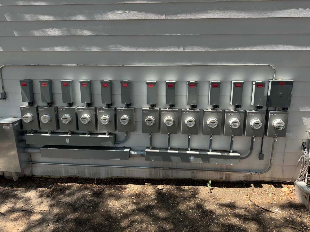 Electrical meters mounted on a building's exterior, with overhead wires and conduit.