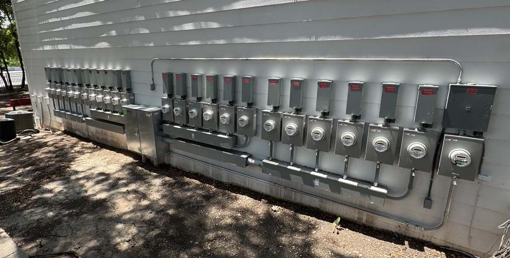 A row of twelve gray electric meters mounted on a white building.