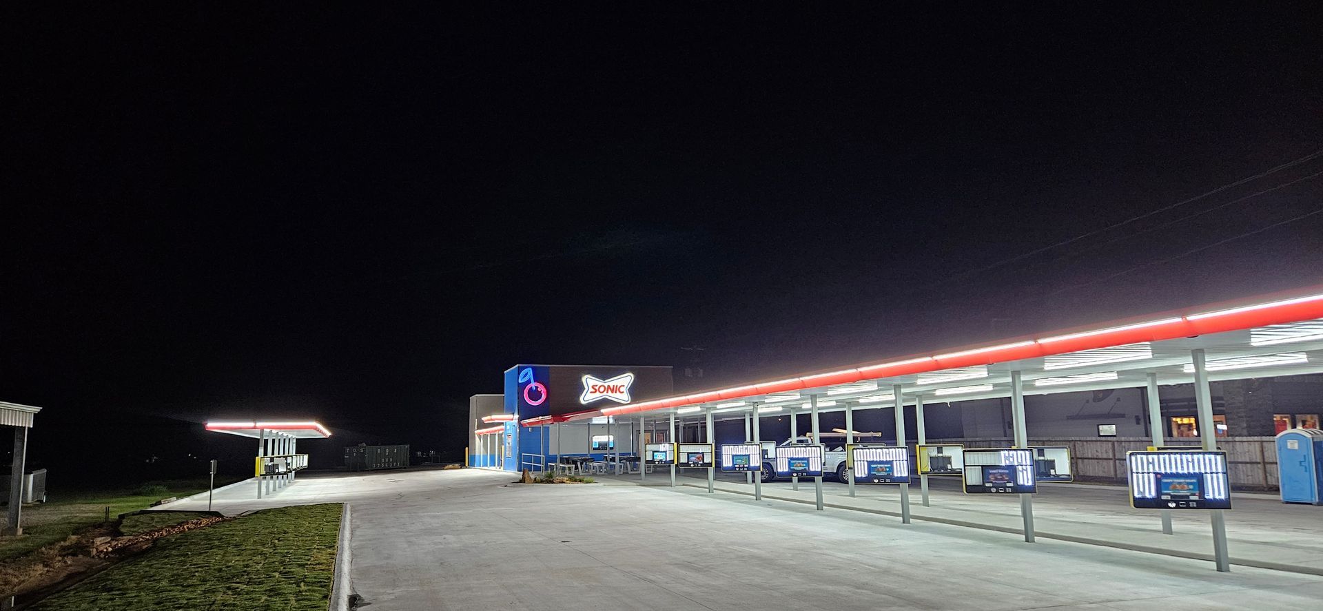 Night shot of a gas station with a long canopy lit with red and blue lights.