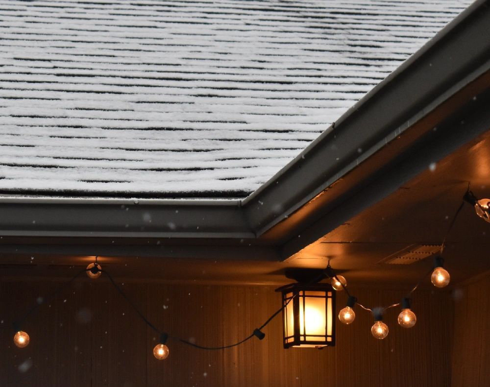 A roof with snow on it and a string of lights hanging from it