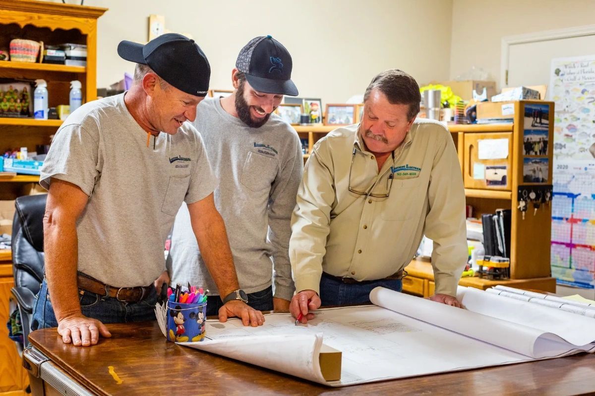 Three men are looking at a blueprint on a table.