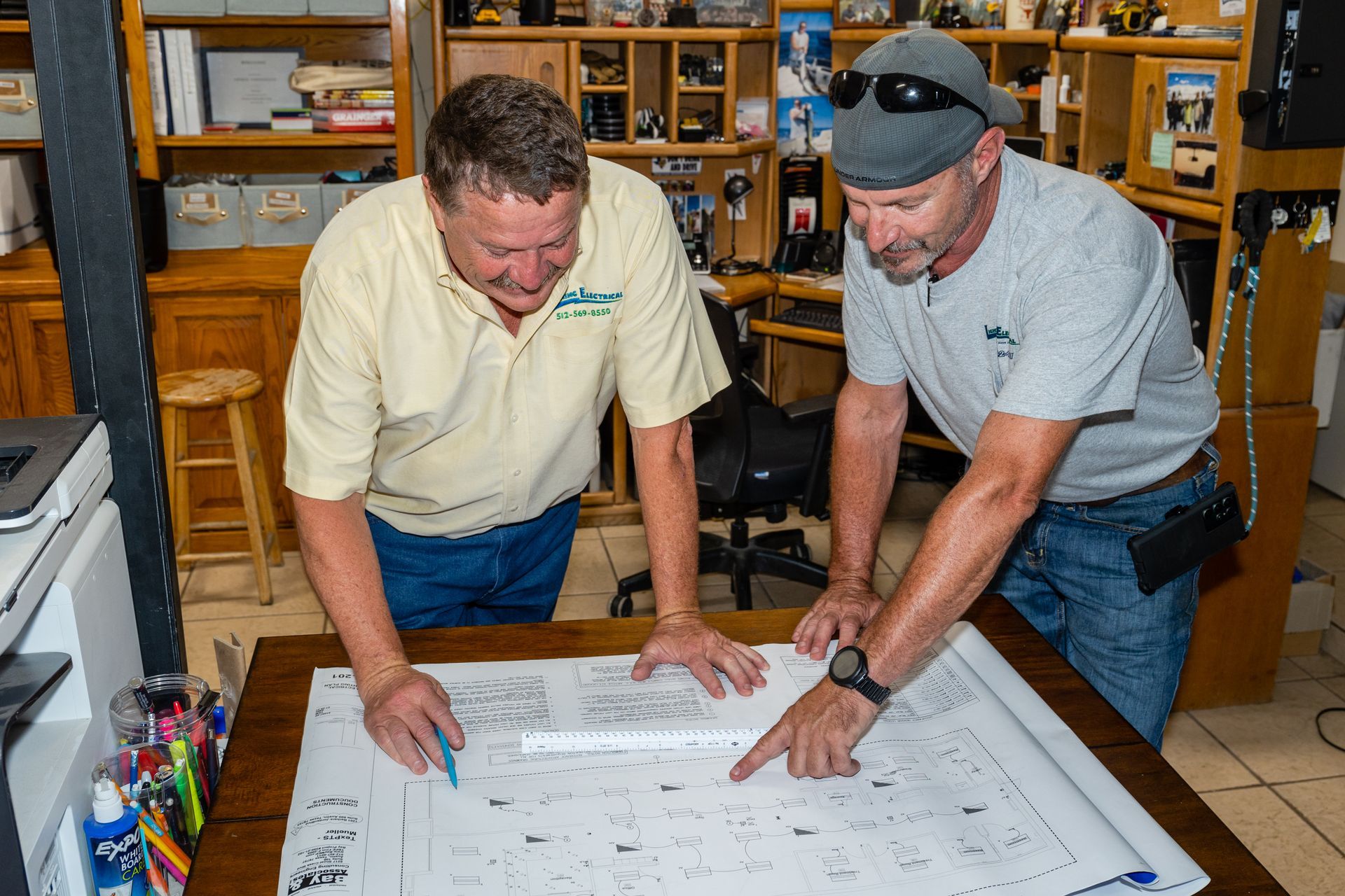 Two men are looking at a blueprint on a table.