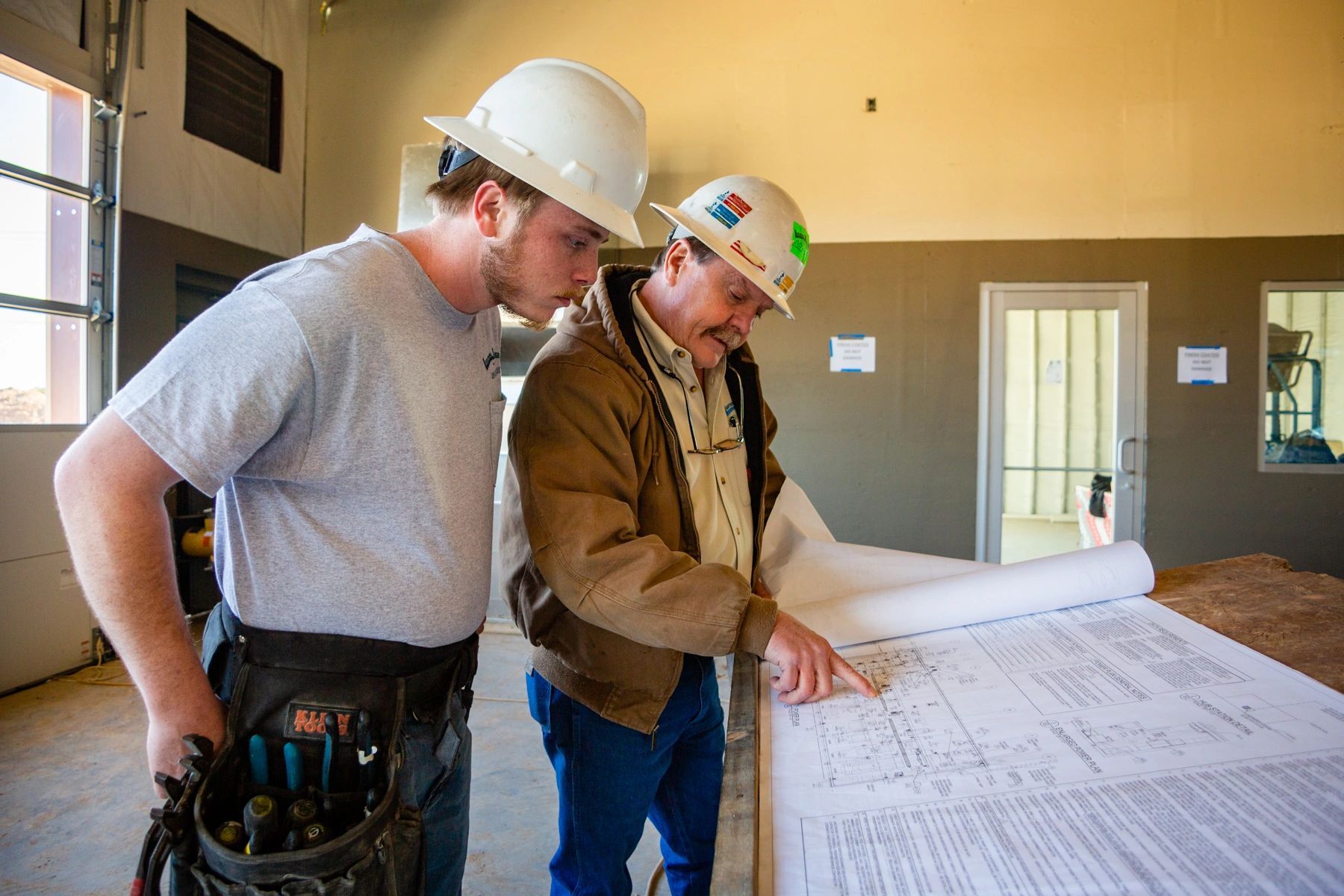 Two men in hard hats are looking at a blueprint.