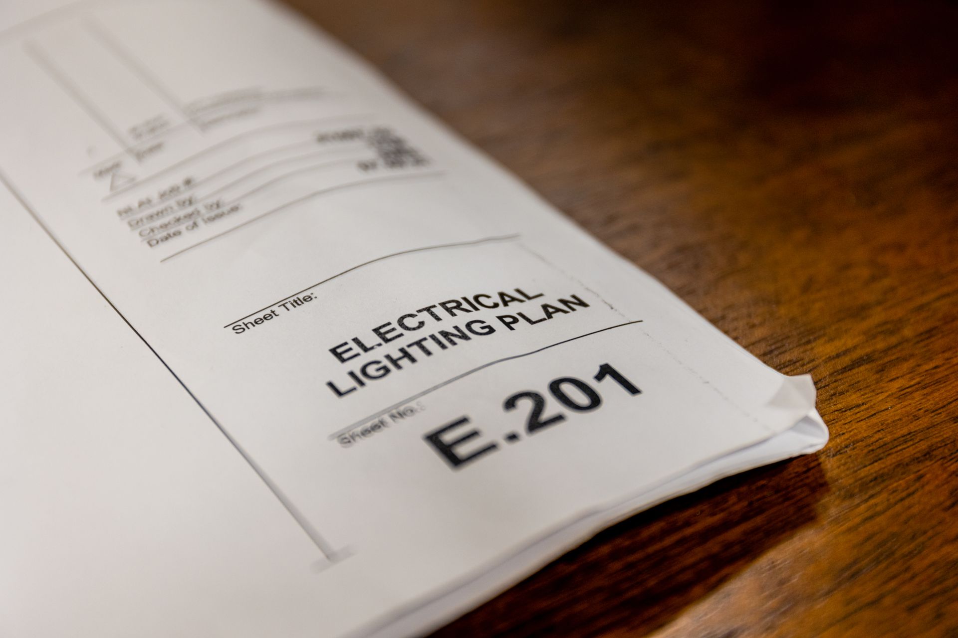 An electrical lighting plan is sitting on a wooden table.