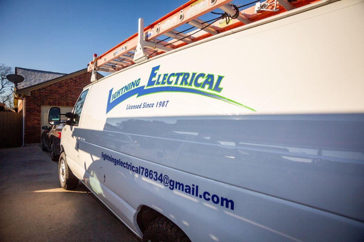 A white van with the word electrical on the side is parked in front of a house.