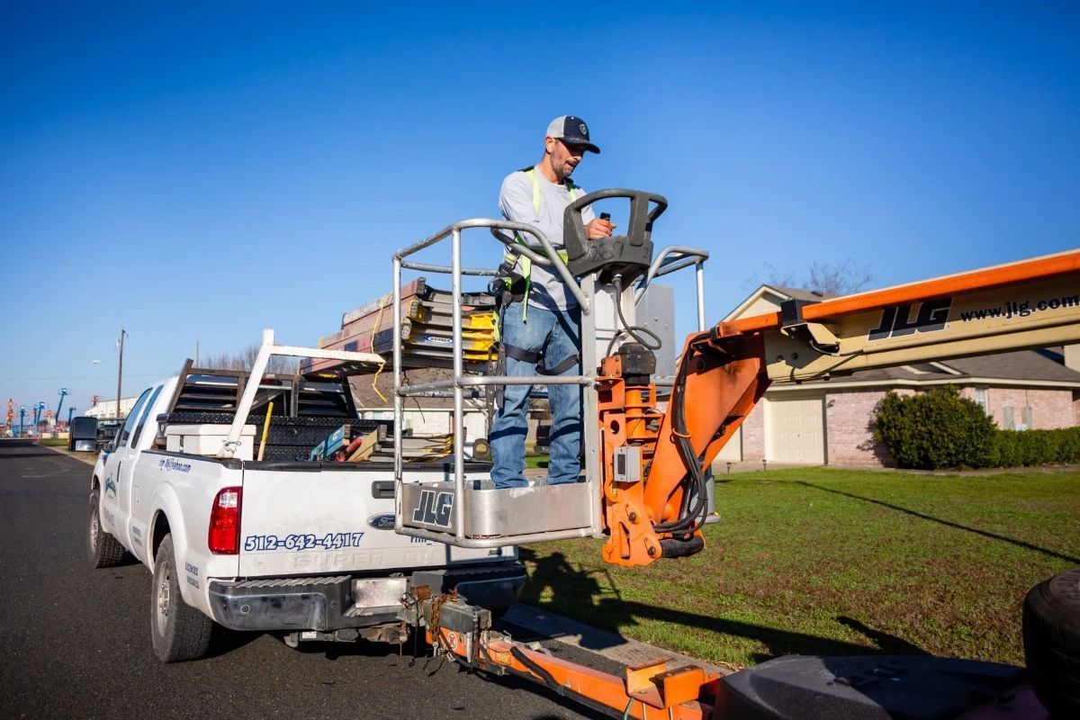 A man is working on a crane in the back of a truck.