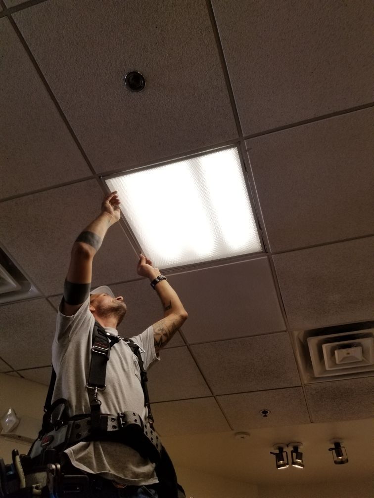 A man is looking up at a light on the ceiling.