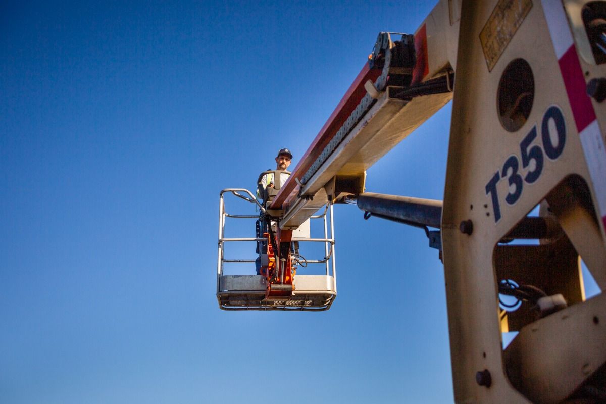 A man is standing in a bucket on a crane.