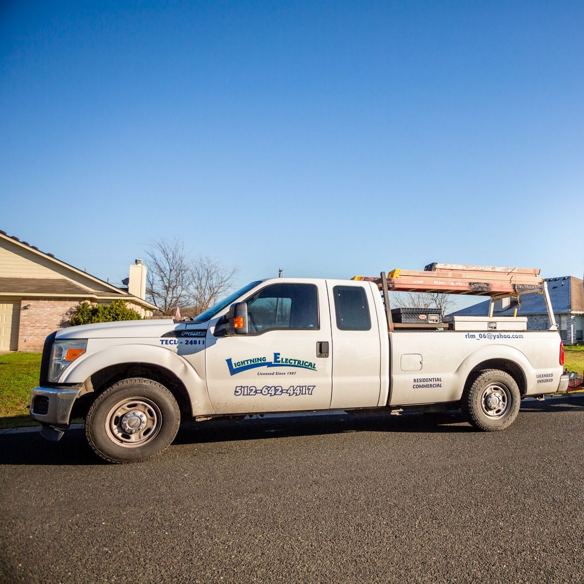 A white truck is parked on the side of the road in front of a house.