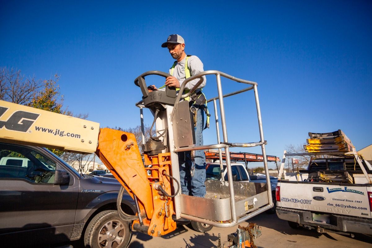 A man is sitting in a lift next to a truck.